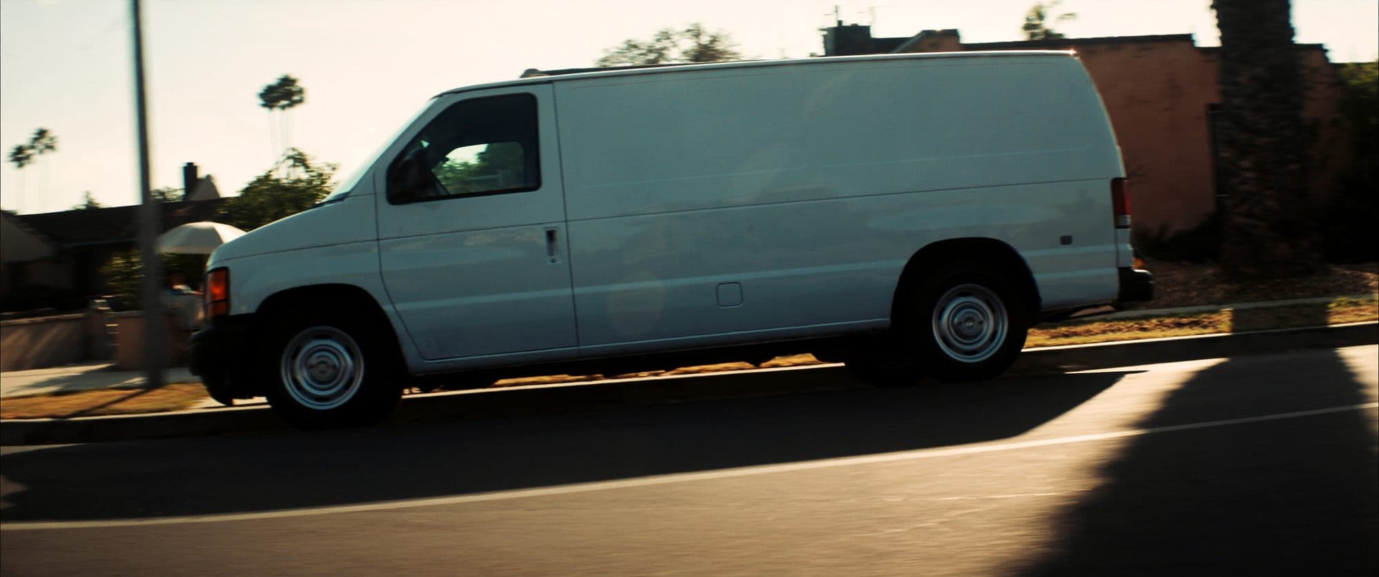 Clean white service van in a suburban driveway with organized tool shelving