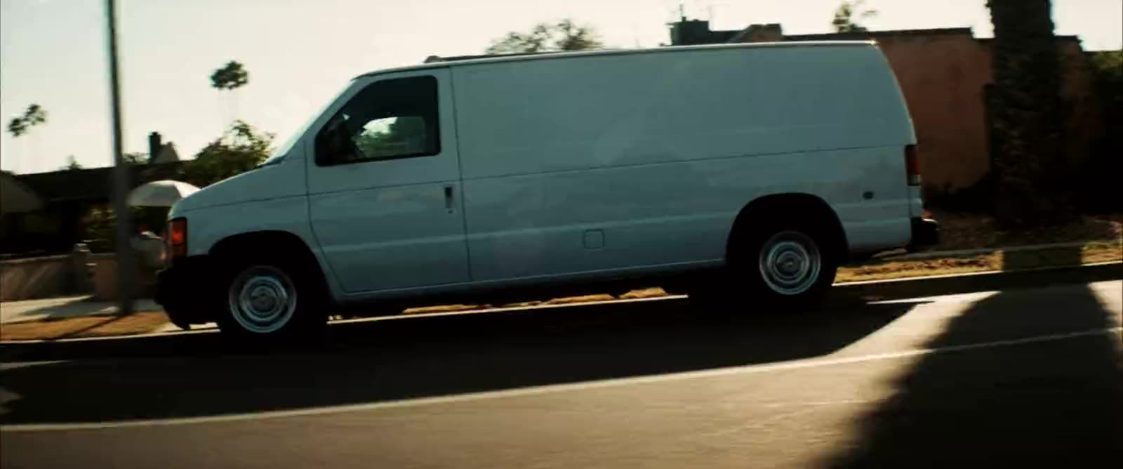 Clean white service van parked in a suburban driveway at golden hour with organized tool shelving visible