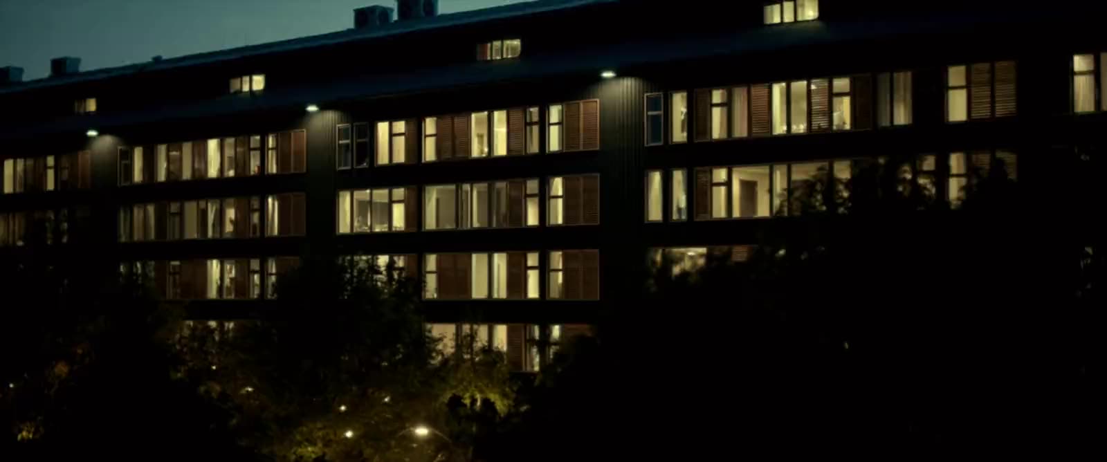 Contemporary four-story multifamily apartment building at golden hour with a landscaped courtyard entry